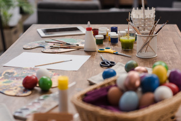 painted easter eggs and tools for painting on wooden table