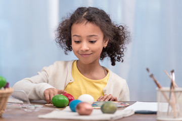 Fototapeta premium adorable african american kid playing with painted easter eggs