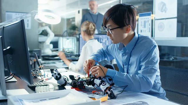 Electronics Engineer Works with Robot Checking Voltage and Program Response time. Computer Science Research Laboratory with Specialists Working.
