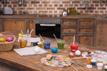 painted easter eggs with paints and brushes on wooden table