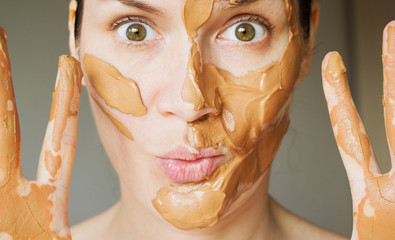 girl puts on a mask of red clay