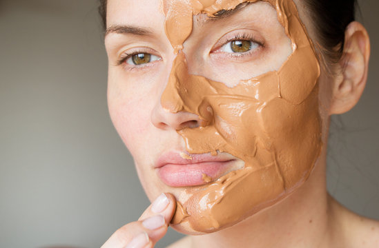 girl puts on a mask of red clay