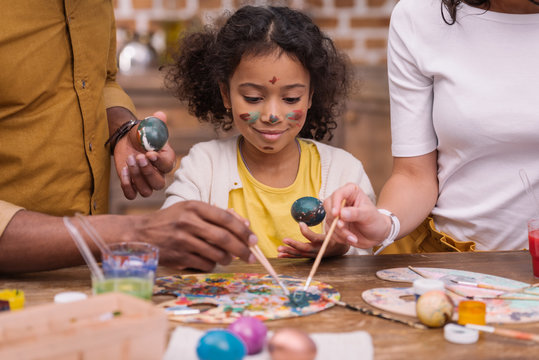 cropped image of african american parents and daughter painting easter eggs