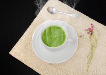 Tea in a white cup, placed on a black wooden floor.