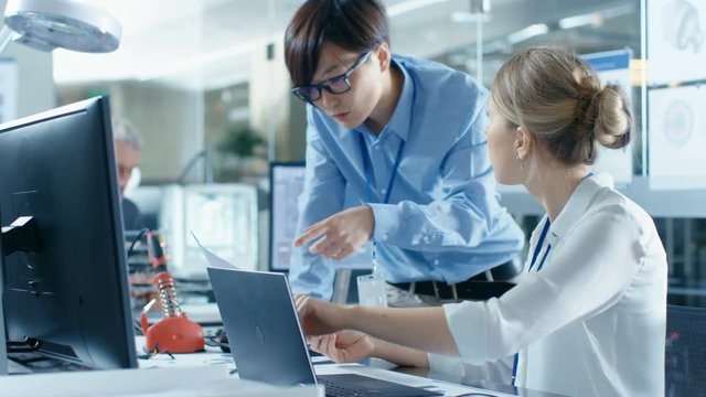 Two Computer Engineers Work with Documents. In The Background Technologically Advanced Scientific Research Center.