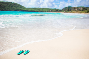 Fototapeta na wymiar Bright flip-flops on a white beach with white sand, turquoise ocean water