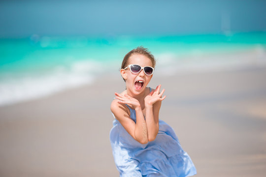 Portrait of happy adorable kid looking at camera background beautiful sky and sea. Little girl in sunglasses smile and enjoy her vacation