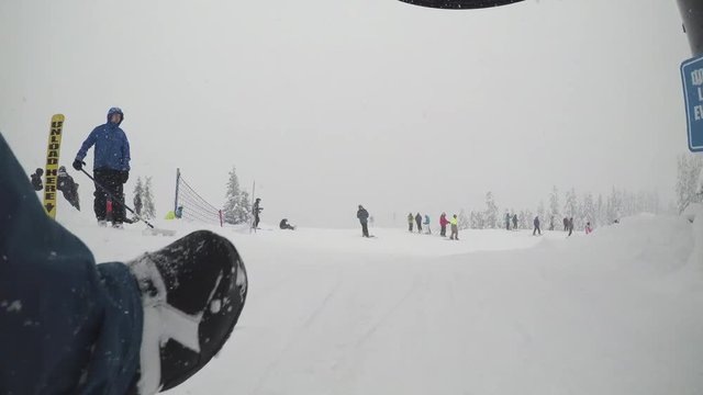 Snowboarder Getting Off Chairlift at Snowy Mountain Resort