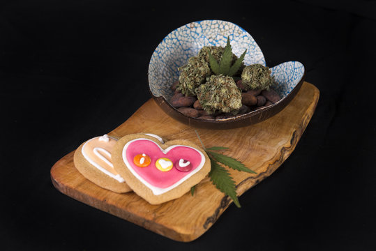 Dried cannabis nugs with cacao beans and baked cookies on a tray
