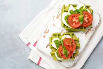 Sandwiches on green wafer with spinach and mozzarella cheese, pesto sauce, tomatoes and basil on a gray concrete old background. Selective focus. Top view.