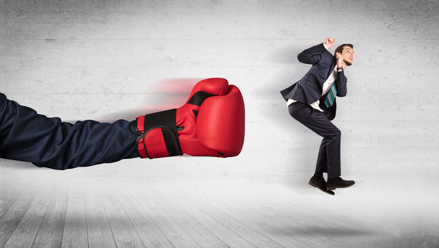 Arm with boxing gloves hits office worker concept