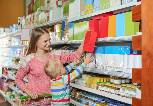 Young mother with little son choosing baby food in supermarket