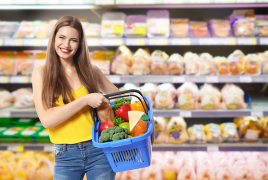 Young woman with basket shopping in supermarket