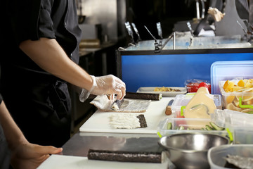 Obraz na płótnie Canvas Chef making tasty maki rolls in restaurant