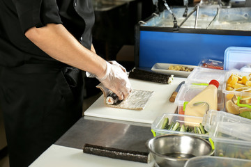 Fototapeta na wymiar Chef making tasty maki rolls in restaurant