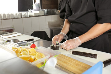 Chef making tasty maki rolls in restaurant