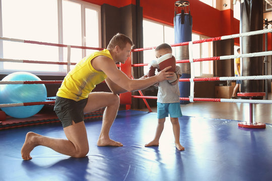 Little boy training with coach in boxing ring