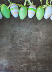 Top view of colorful green, orange, white and yellow easter eggs decorations on old rustic vintage wooden background, easter decoration background or concept