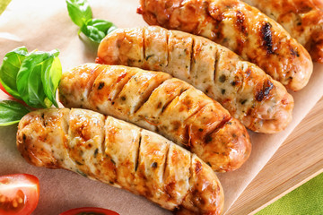 Delicious grilled sausages on wooden board, closeup