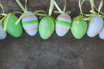 Top view of colorful green, orange, white and yellow easter eggs decorations on old rustic vintage wooden background, easter decoration background or concept