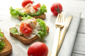Marble board with tasty chicken bruschettas, closeup