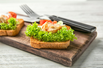 Wooden board with tasty chicken bruschettas on table