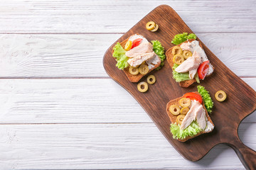 Wooden board with tasty chicken bruschettas on table
