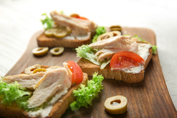 Fototapeta na wymiar Wooden board with tasty chicken bruschettas, closeup