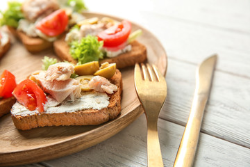 Wooden plate with tasty chicken bruschettas, closeup