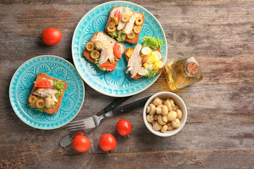 Plates with tasty chicken bruschettas on wooden table