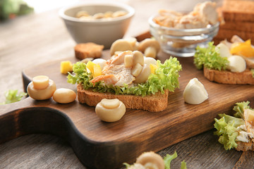 Wooden board with tasty chicken bruschetta, closeup