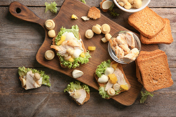 Wooden board with tasty chicken bruschettas on table