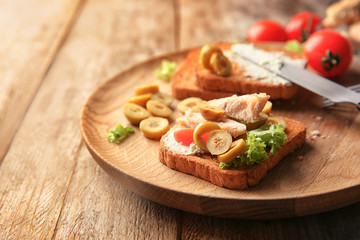 Plate with tasty chicken bruschetta on wooden table