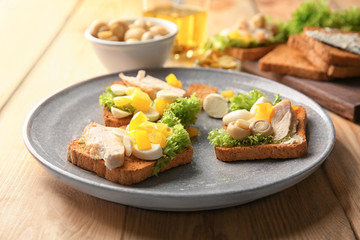 Plate with tasty chicken bruschettas on table