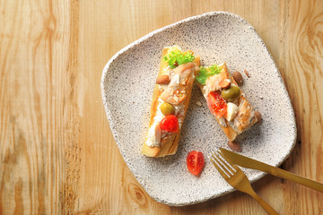 Plate with tasty chicken bruschettas on wooden table