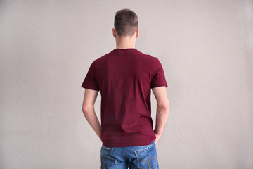 Young man in color t-shirt on light background. Mockup for design