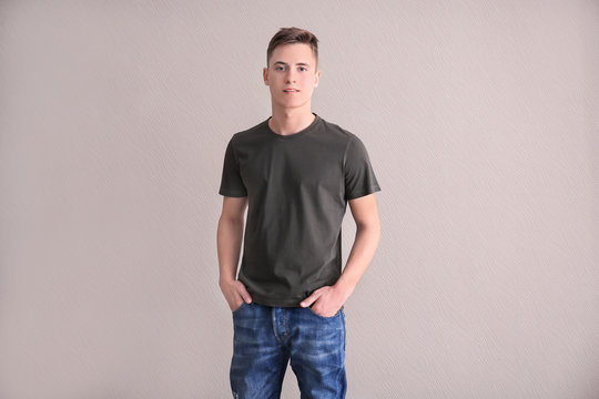 Young man in color t-shirt on light background. Mockup for design