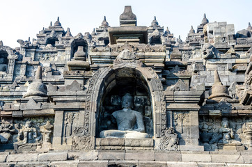 Fototapeta na wymiar Multiple ancient stone sculptures of Buddha on the relief in Borobudur Temple in Yogyakarta, Java, Indonesia.