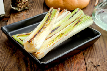 leeks roasted on the grill in square tray, on classic wood