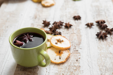 Obraz na płótnie Canvas mulled wine in a green Cup scattered slices of dried apples and anise stars, toned background design