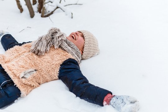 A girl lying on the snow and doing a snow angel. active life consept