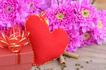 Fototapeta na wymiar A red heart with red gift box, wooden hearts shape and Pink flower on wooden table background , Love, Wedding and Valentine's day concept.