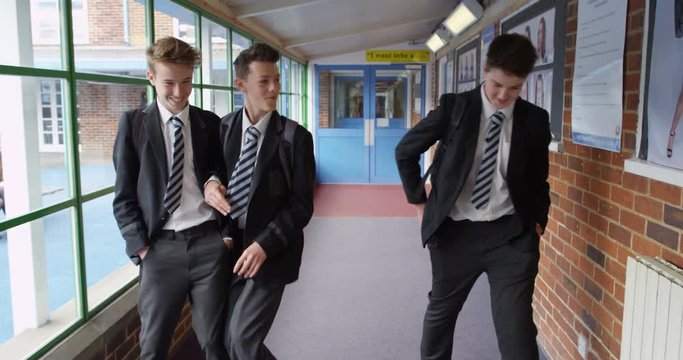 4K Young schoolboys play fighting as they walk through school building. Slow motion