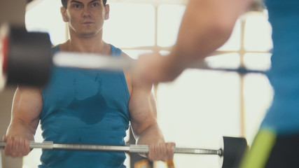 Bodybuilding in the gym - muscular man training his biceps near mirror