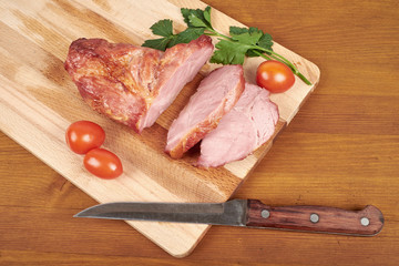 Cooked sliced pork barbecue steak on wooden cutting board.