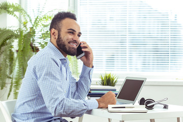 portrait of handsome African black young business man working on laptop at office