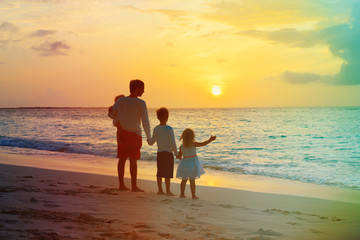 Fototapeta na wymiar father and kids walking on beach at sunset