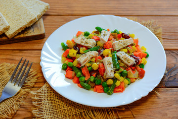 Chicken breast and mixed vegetable stew on the serving plate and the wooden table. Low-calorie chicken vegetable stew. Stewed carrots, green beans, peas, corn and pepper with boiled chicken breast