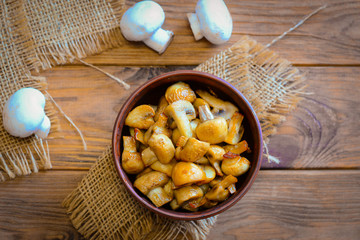 Roasted mushrooms. Homemade roasted mushrooms in a bowl on a wooden background. Vegetarian low-calorie dinner recipe. Top view