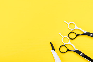 pair of scissors for a hairstyle lay in a corner on a yellow background